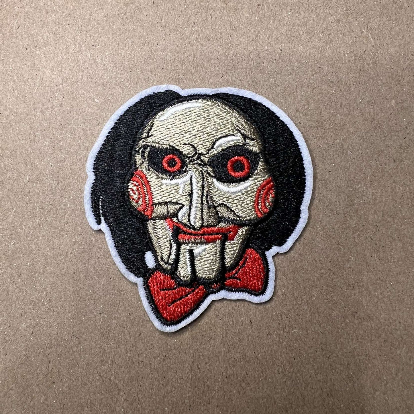 Brodert strykemerke av Billy The Puppet fra filmserien Saw