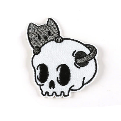 Brodert strykemerke av katt som gjemmer seg bak en hodeskalle