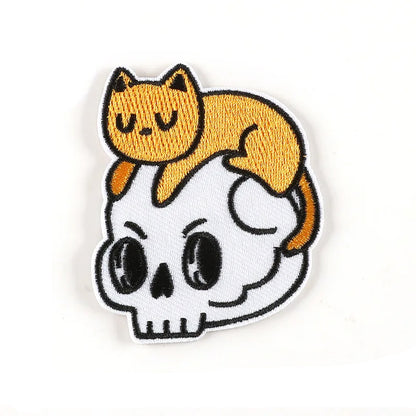 Brodert strykemerke av katt som leker oppå en hodeskalle
