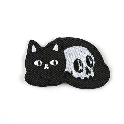 Brodert strykemerke av sort katt som ligger inntil en hodeskalle