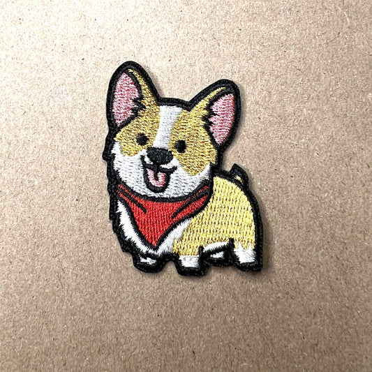 Brodert strykemerke av lysebrun og hvit hund med rødt skjerf