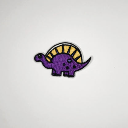 Strykelapp med motiv av lilla og gul Dino