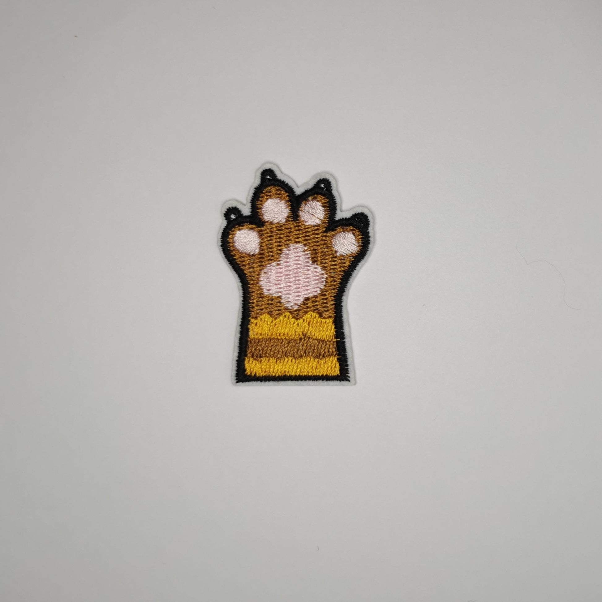 Brodert strykemerke av kattepote, brun og gul