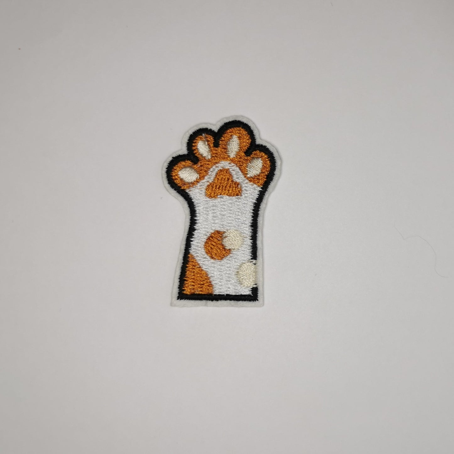 Brodert strykemerke av kattepote, hvit og brun