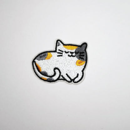 Brodert strykemerke med hvit katt med gule og grå tegninger i pelsen