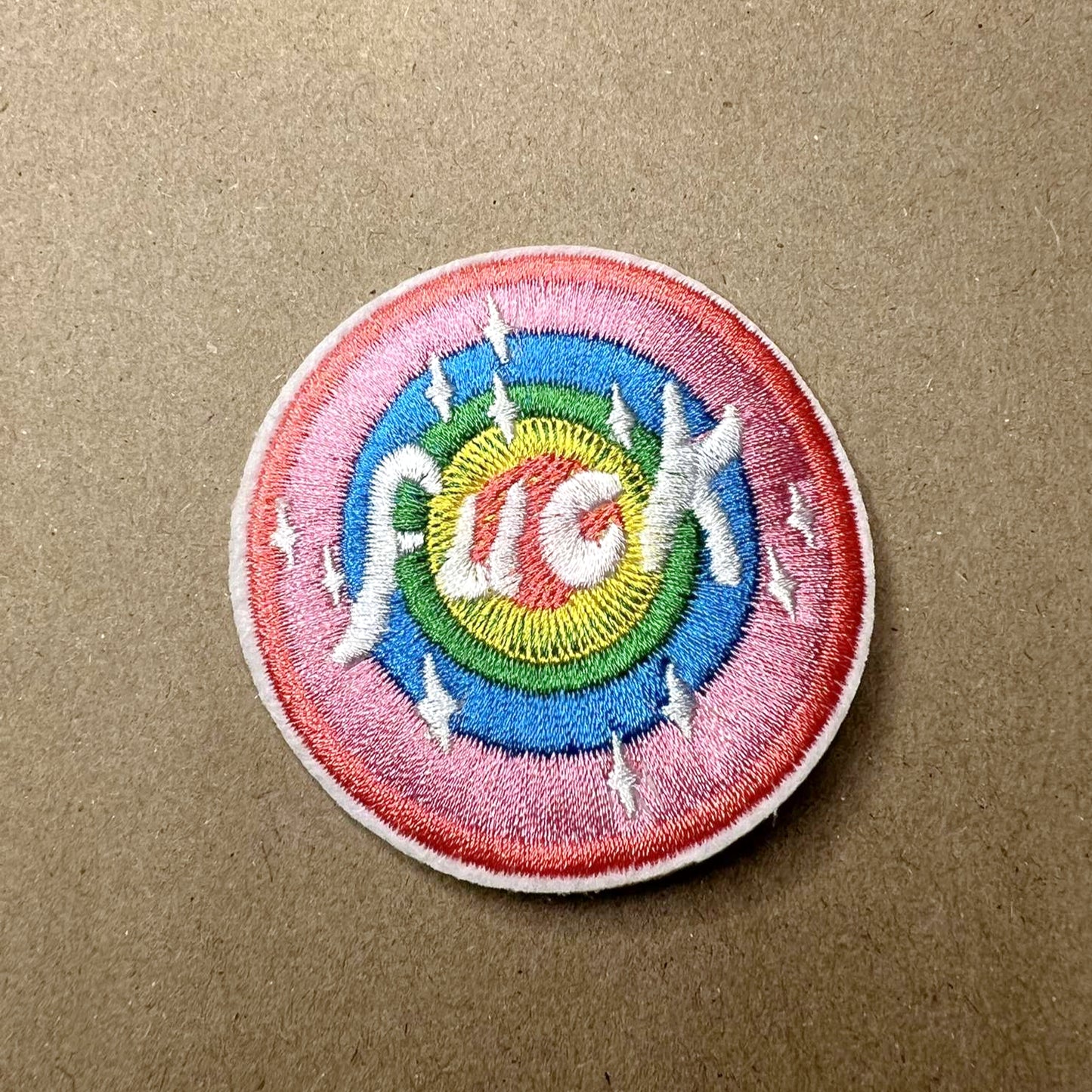 Brodert strykemerke med Pridefarger og teksten Fuck