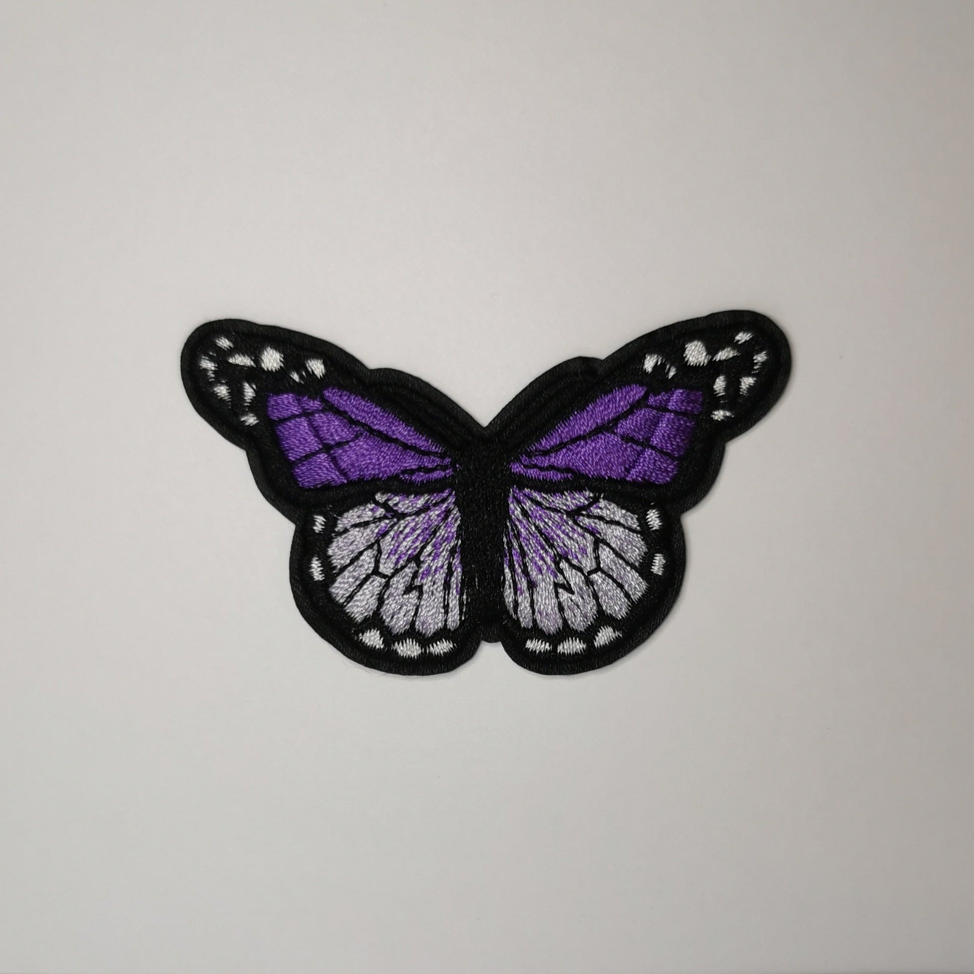 Brodert strykemerke, lilla, sølv og hvit sommerfugl
