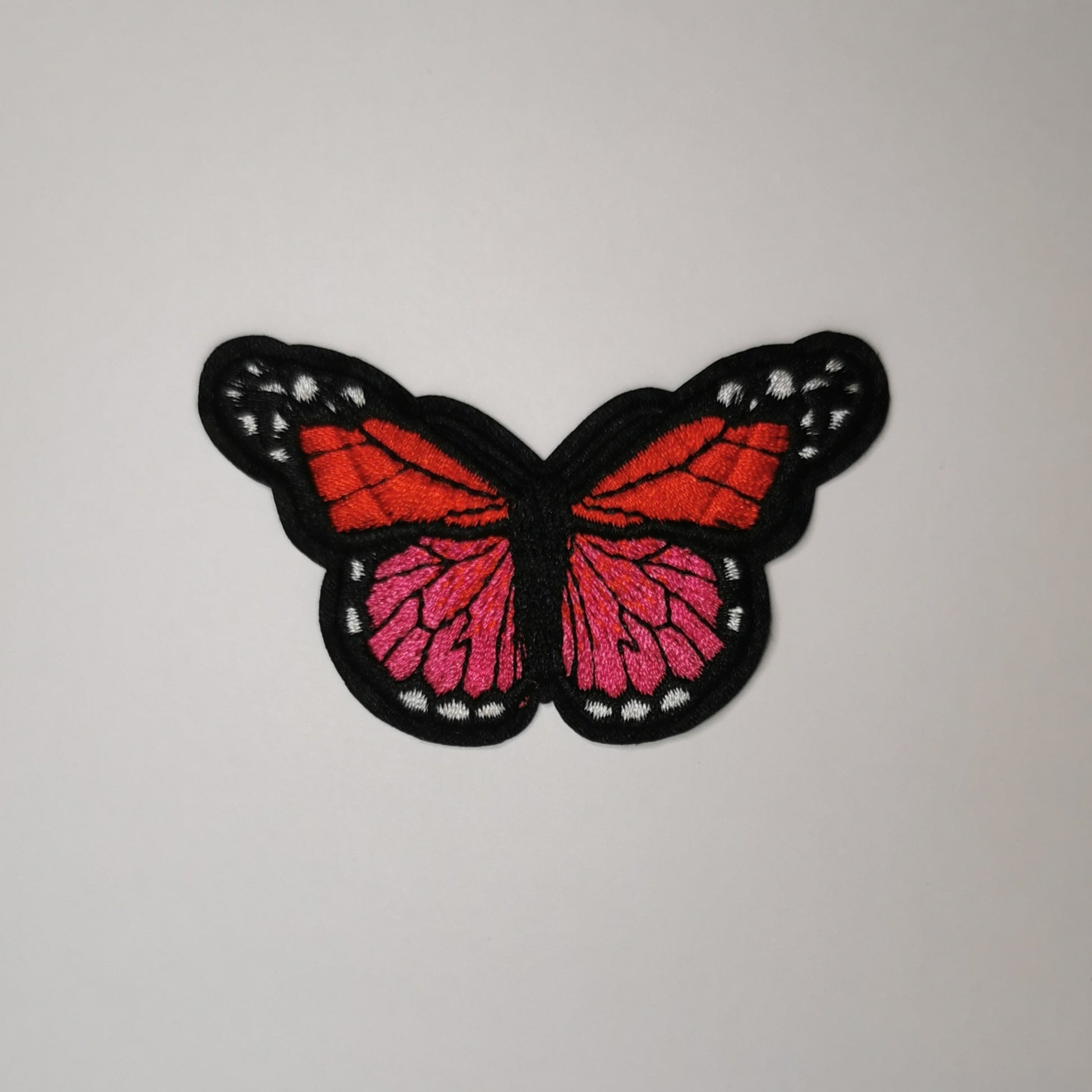 Brodert strykemerke, rød, mørk rosa og hvitsommerfugl